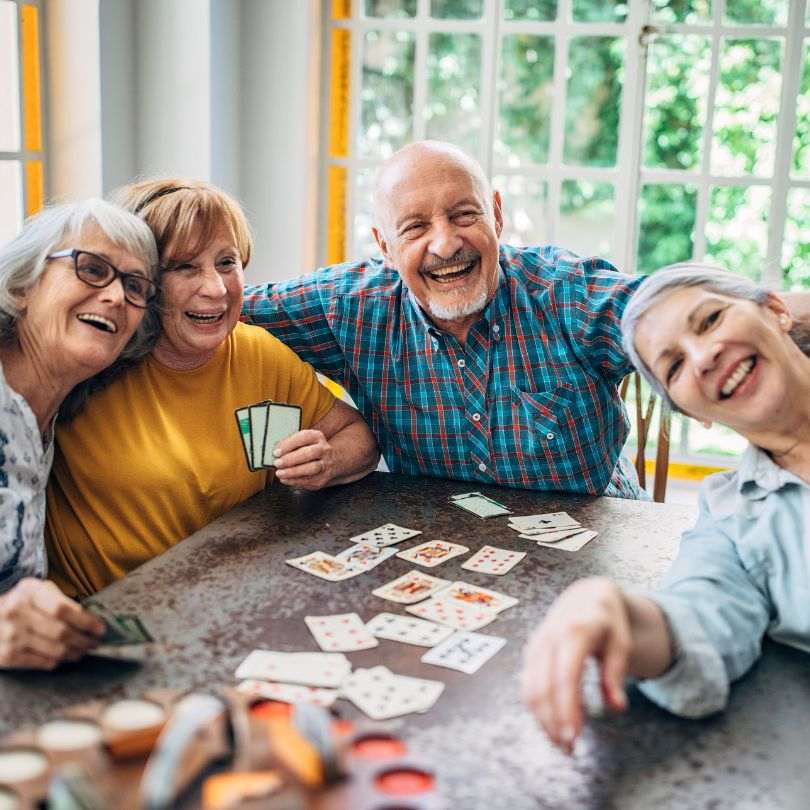 Group of happy seniors playing cards